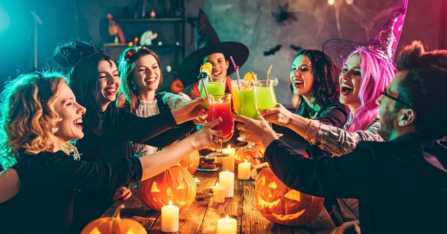 A group of participants is cheering with their drinks at a Halloween party