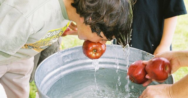 A child is playing the traditional Halloween party game, Apple Bobbing
