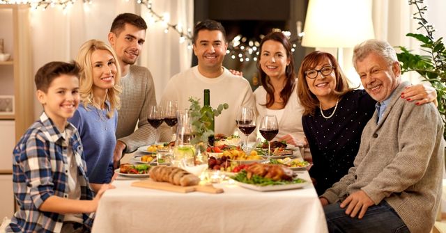 A group of family at their Thanksgiving dinner, happily smiling for photos. 