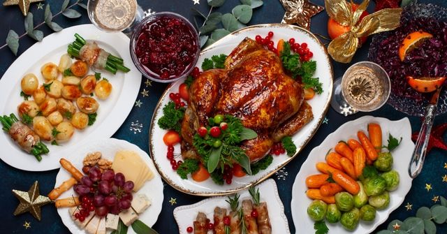 Festive Christmas dinner table with golden roast turkey centerpiece, surrounded by seasonal side dishes