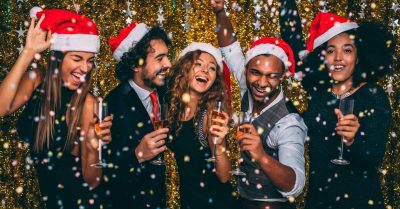 Five colleagues wearing Santa hats enjoy a work Christmas party theme joyfully 