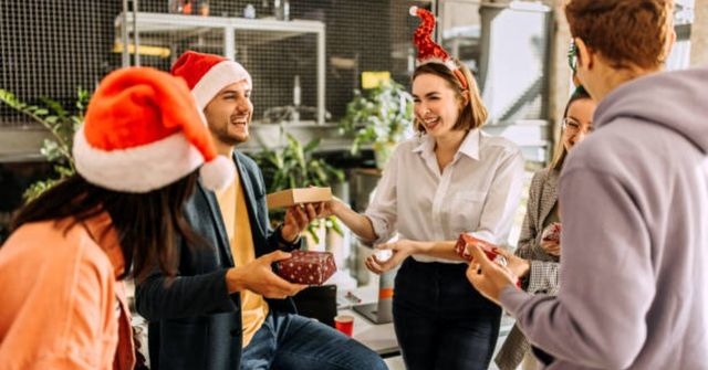 A group of office workers at their work Christmas party, joyfully smiling and talking to each other