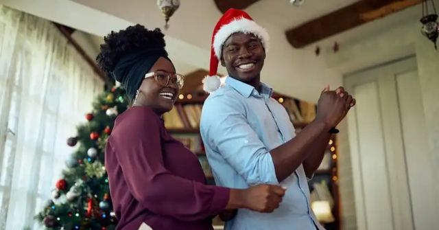 A couple stand laughing and presenting their Emoji Christmas Story game