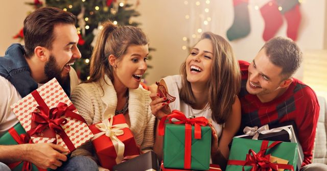 Four colleagues holding Christmas gifts, miling and guessing their Secret Santa