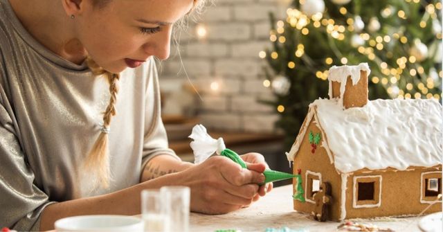 A female employee decorates a gingerbread house during a work Christmas party game