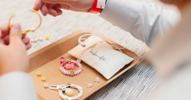 A participant assembles a beaded keychain on a wooden tray