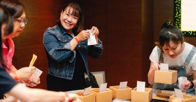 Three event attendees engage cheerfully in a herbal sachet workshop