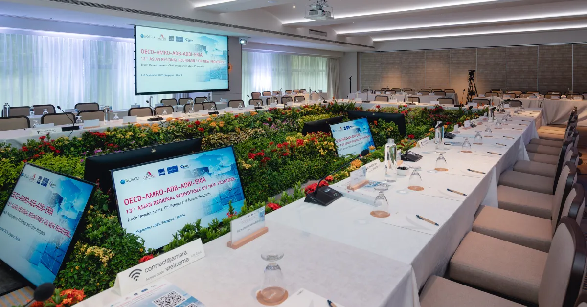 A conference room with U-shaped table setup adorned with lush greenery and branded elements. 