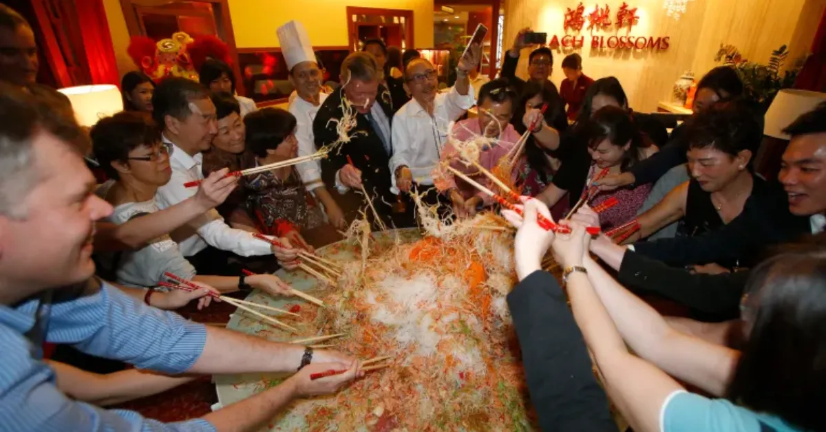 A group of colleagues participating in lo hei tossing as a Chinese New Year party idea