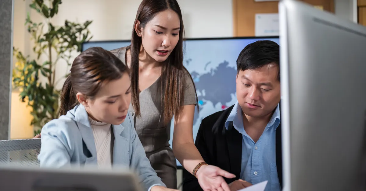 Three colleagues at a desk reviewing their corporate event planning