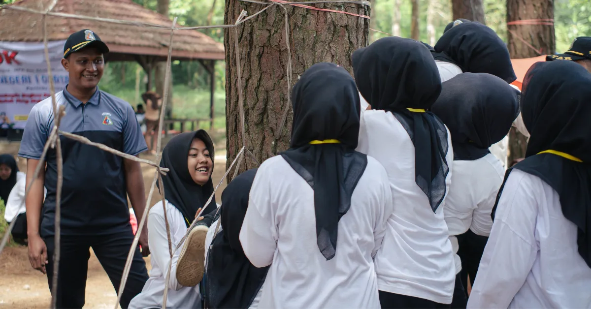 Female employees in white shirts and black headscarves participate in a team-building activity in a forest