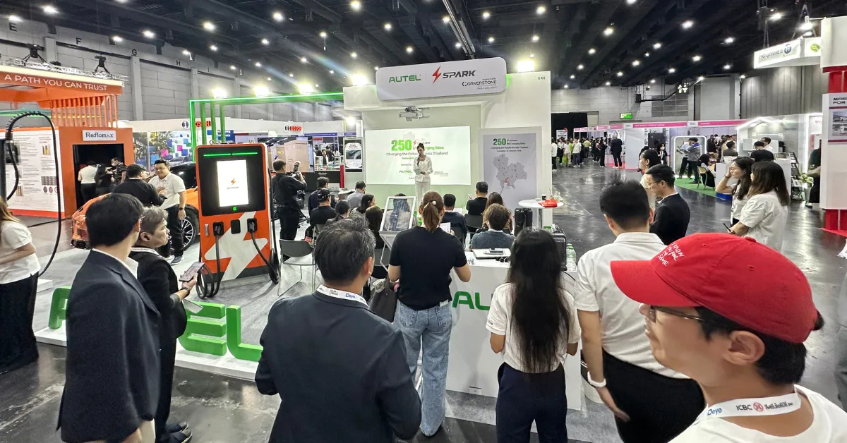 A crowd gathers at a tech conference booth with a presenter on stage