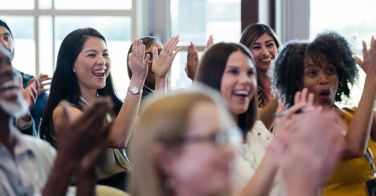 Attendees happily clapping their hands and enjoying themselves at an event
